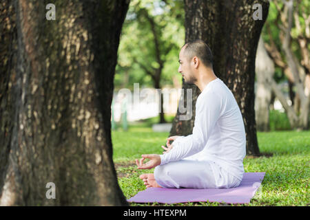 Man doing yoga exercises in the park Stock Photo