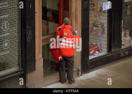 Royal Mail postman delivering letters street doorway buzzer Stock Photo