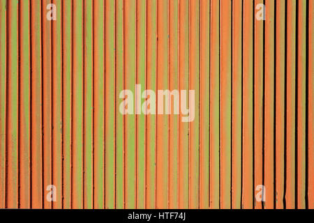 Orange rusty green background. Corrosion of metal iron. Vertical fence Stock Photo