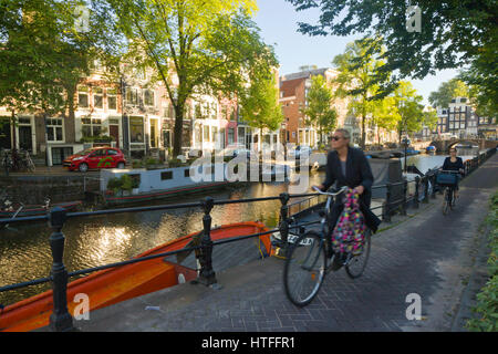 Cycling to work along one of Amsterdam's canal tow paths, on a sunny morning Stock Photo