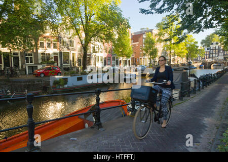 Cycling to work along one of Amsterdam's canal tow paths, on a sunny morning Stock Photo