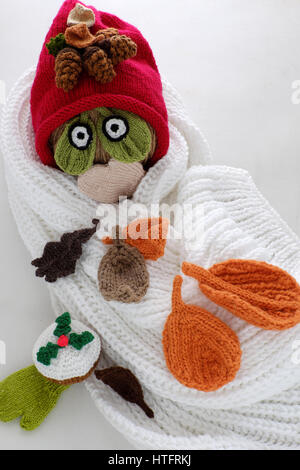 Diy funny, humor Christmas background handmade, lazy snowman from white scarf, red hat, eye, knitted leaf, winter leaves in cold day of Xmas holiday Stock Photo
