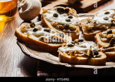 Crostini with fried mushrooms, onion and mozzarella cheese on a plate Stock Photo
