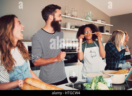 Four happy friends playing with food while cooking for dinner or a culinary class indoors Stock Photo