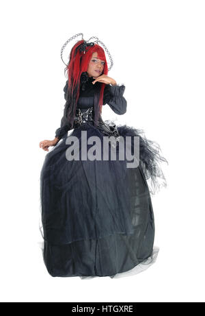 A young beautiful African American woman standing in a long black Victorian dress and red hair, isolated for white background. Stock Photo