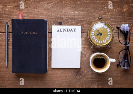 Holy Bible, alarm clock, glasses and coffee on wood table. Studying  the Bible concept. Stock Photo