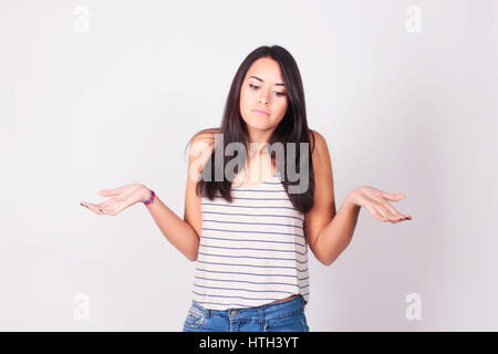 Young woman shrugging her shoulders. Portrait of a woman with clueless expression. Stock Photo