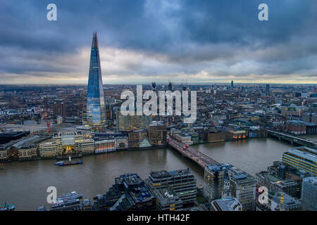 Panoramic aerial view of urban London with the Shard skyscraper and Thames river at sunset against a cloudy sky. London, United Kingdom. Stock Photo