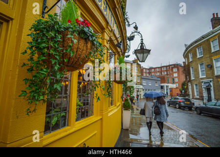 Corner shop and beautiful brightly coloured houses in the famous Notting Hill against a cloudy sky. London, United Kindom. Stock Photo