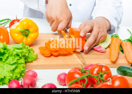 preparation of cutting vegetables for salad, close up hands of chef with knife Stock Photo