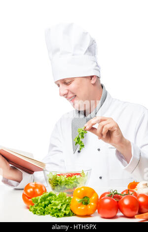 cheerful cook with a cookbook, prepares a salad according to prescription Stock Photo