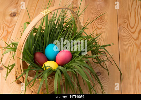 basket with green grass and Easter eggs on wooden boards Stock Photo