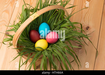 basket with Easter eggs with green grass on a wooden table Stock Photo