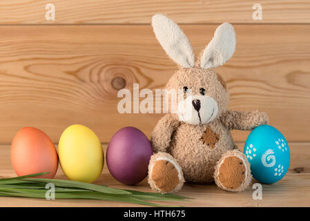 easter bunny and colored eggs in a row on a wooden background Stock Photo