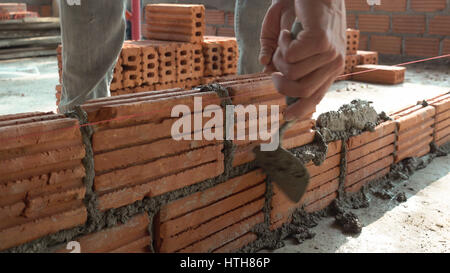 Bricklayer worker installing brick masonry on exterior wall with trowel putty knife Stock Photo