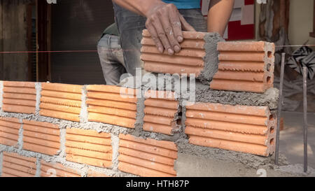 Bricklayer worker installing brick masonry on exterior wall with trowel putty knife Stock Photo
