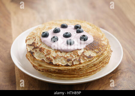 blini or crepes with yogurt and blueberries on wood table, sweet breakfast Stock Photo
