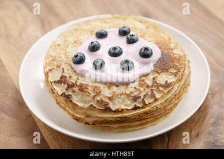 blini or crepes with yogurt and blueberries on wood table, sweet breakfast Stock Photo