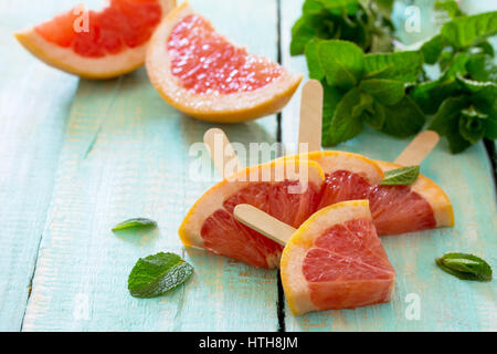 Summer background. Slices of red grapefruit popsicle on a vintage wooden background. Stock Photo