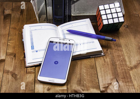 Books, diary with pen, smartphone and cube Rubik lie on a wooden surface Stock Photo