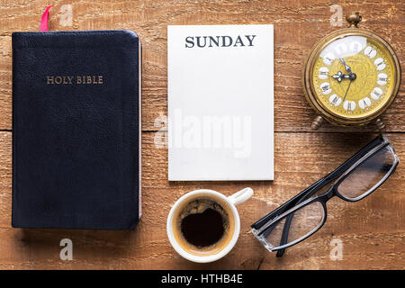 Holy Bible, alarm clock, glasses and coffee on wood table. Studying  the Bible concept. Stock Photo