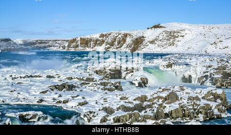 A frozen waterfall in Iceland with blue sky on winter day Stock Photo