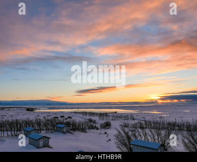 Colourful sunrise on a low horizon in winter in Iceland, with bungalow chalets in foreground Stock Photo