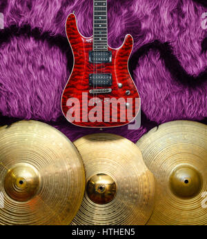 Red Electric guitar with three cymbals on faux fur wall. Musical instruments background Stock Photo
