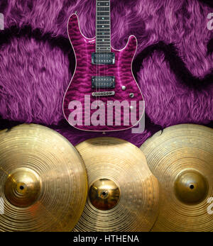 Purple electric guitar with three cymbals on faux fur wall. Musical instruments background Stock Photo