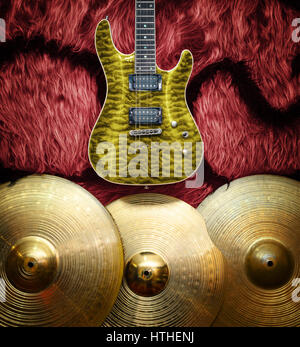Yellow electric guitar with three cymbals on faux fur wall. Musical instruments background Stock Photo