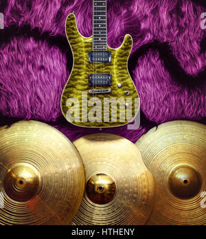 Yellow electric guitar with three cymbals on pink faux fur wall. Musical instruments background Stock Photo