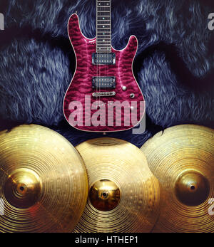 Purple electric guitar with three cymbals on faux fur wall. Musical instruments background Stock Photo