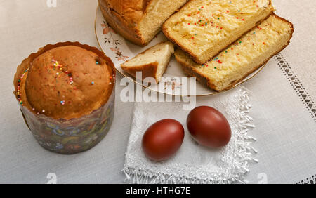On the table on a white cloth with two red Easter eggs next to the cake in a beautiful package. Stock Photo