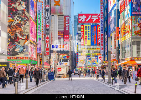 TOKYO, JAPAN - JANUARY 11, 2017: Crowds pass below colorful signs in Akihabara. The historic district electronics has evolved into the shopping area f Stock Photo