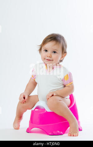 Little smiling girl sitting on a pot. Isolated on white background. Stock Photo