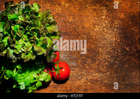 Top view of bunches of fresh herbs and tomatoes on wooden board Stock Photo