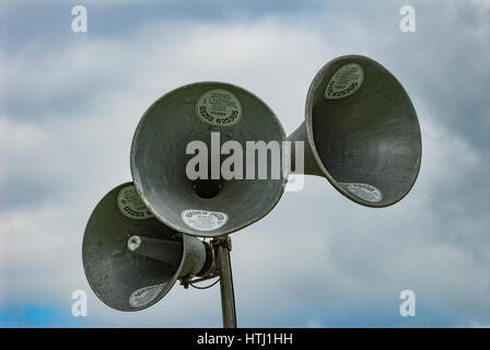 A trio of horn shaped loudspeakers with a cloudy blue sky background. Stock Photo