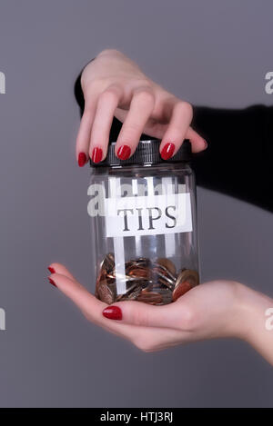 Woman's hands holding a screw cap jar for tips Stock Photo
