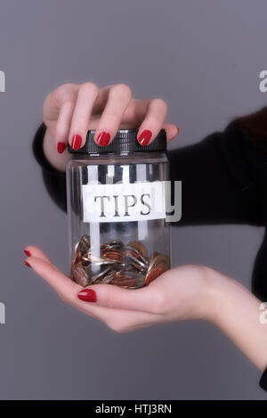 Woman's hands holding a screw cap jar for tips Stock Photo