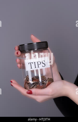 Woman's hands holding a screw cap jar for tips Stock Photo