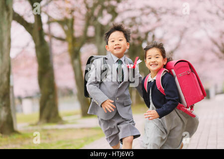 Japanese kids with cherry blossoms in a city park Stock Photo