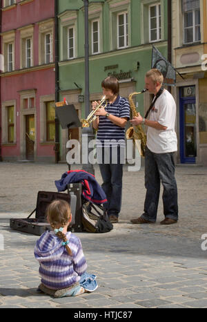 Young girl listening to street musicians playing jazz at Rynek (Market Square) in Wroclaw, Lower Silesia, Poland Stock Photo