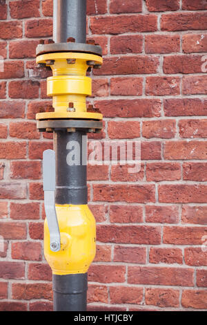 Gas tubing with open valve above red brick wall Stock Photo