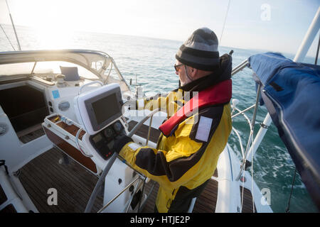 Man Operating Navigational Screen On Sail Boat In Sea Stock Photo