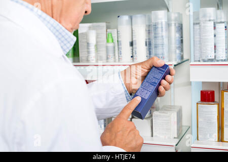 Midsection Of Pharmacist Reading Instructions On Medicine Box Stock Photo