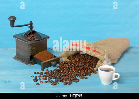 Coffee grinder and coffee beans in bag. Blue background. Stock Photo