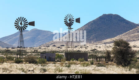Two windmill water pumps in the heat haze on farm Stock Photo