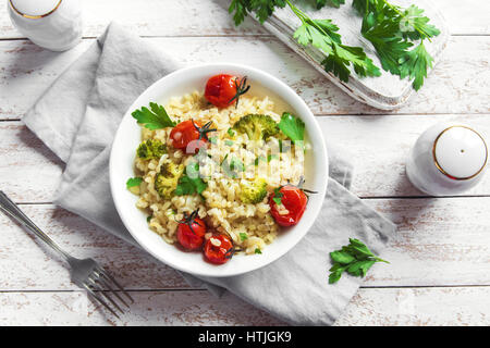 Bulgur with Vegetables: tomatoes, broccoli and parsley on white wooden background - healthy homemade organic vegan vegetarian diet food Stock Photo