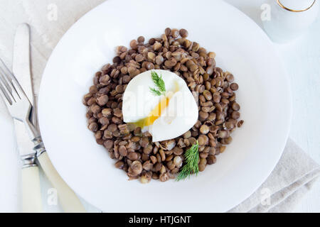 Lentil and soft poached egg with dill on white plate - healthy organic homemade lunch Stock Photo