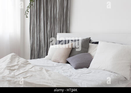 Bed with white and grey linens and a lot of pillows Stock Photo